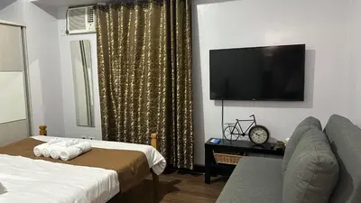 a hotel room with a bed and a flat screen tv at Condo Unit at La Verti Residences in Manila