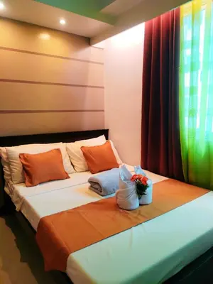 a bed in a room with orange pillows and a window at Comfystay at Sea residences 2 bedrooms in Manila