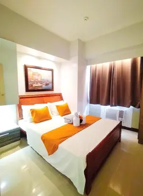 a bedroom with a large bed with orange and white sheets at Comfystay at Sea residences 2 bedrooms in Manila