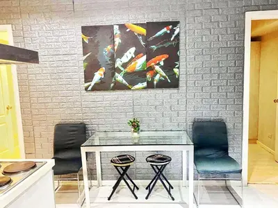 a table with two chairs and two paintings on a wall at 2bedroom azure beachview 7 in Manila