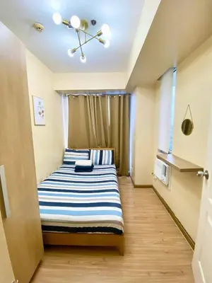 a bedroom with a bed with blue and white stripes at 2 bedroom azure cityview 1 in Manila