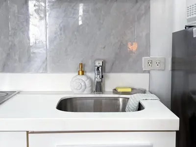a white kitchen with a sink and a refrigerator at Sky Piea at Knightsbridge Residences - APARTMENT with Gym Sauna Pool in Manila
