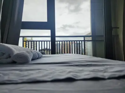 a bed in a bedroom with a view of a balcony at Bayport Luxhome in Manila