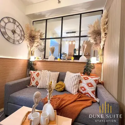 a living room with a couch and a clock on the wall at Aesthetic walking distance to MOA,near NAIA AIRPORT with NETFLIX,MINIVIDEOKE,BOARDGAMES-DUXE9 in Manila