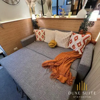 a couch with a blanket and pillows on it at Aesthetic walking distance to MOA,near NAIA AIRPORT with NETFLIX,MINIVIDEOKE,BOARDGAMES-DUXE9 in Manila