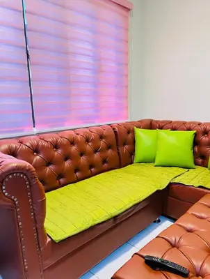a brown leather couch with two green pillows on it at Transient Room in Dasmariñas
