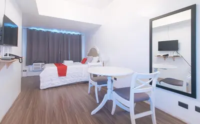 a room with a bed and a table and a mirror at RedDoorz at MPT Suites Test in Manila