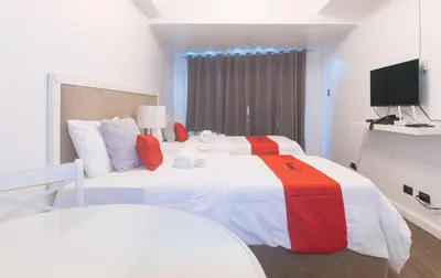 a bedroom with two beds and a flat screen tv at RedDoorz at MPT Suites Test in Manila