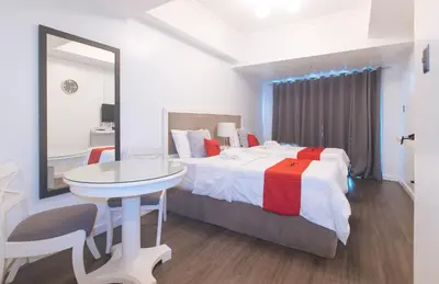 a bedroom with a bed and a table and a mirror at RedDoorz at MPT Suites Test in Manila