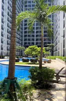 a pool with palm trees and buildings in the background at Aesthetic walking distance to MOA,near NAIA AIRPORT with NETFLIX,MINIVIDEOKE,BOARDGAMES-DUXE5 in Manila