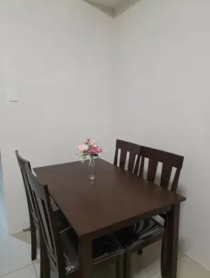 a wooden table with a vase of flowers on it at Staycation with Netflix in Shell Residences in Manila