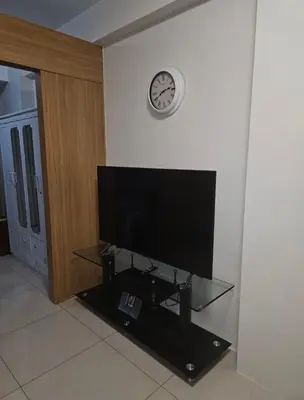 a living room with a tv and a clock on the wall at Staycation with Netflix in Shell Residences in Manila