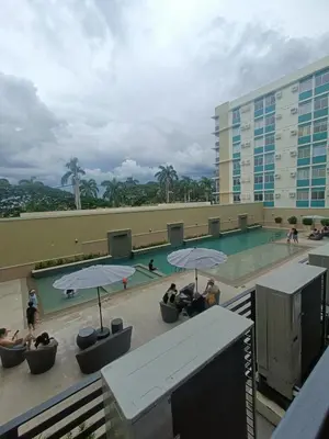 a swimming pool with people sitting under umbrellas at DongStay in Bayabasan
