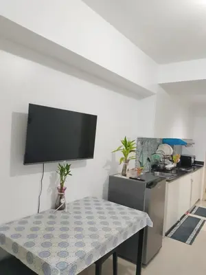 a kitchen with a table and a tv on the wall at Tower C sea residence manolita in Manila