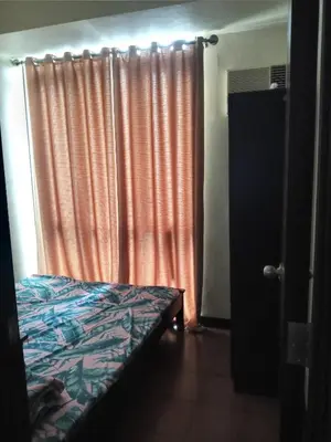 a bedroom with a bed and an orange curtain at Condo staycation in SLP Bangkal Makati in Manila