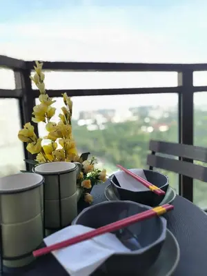 a table with chopsticks and plates and a vase with flowers at Condo Unit Near Manila Bay, US Embassy & Iconic Tourist Spots in Manila