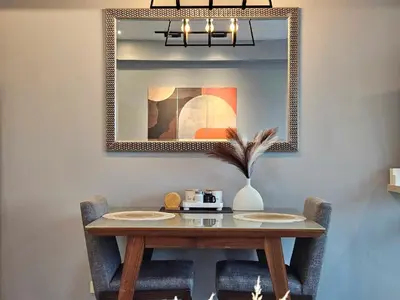 a dining room table with two chairs and a mirror at Ashley's Chamber at Soho Central across Shangrila Mall in Manila