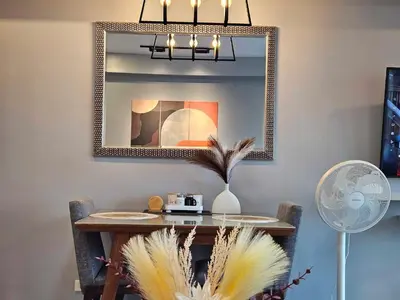 a dining room table with a mirror and a fan at Ashley's Chamber at Soho Central across Shangrila Mall in Manila