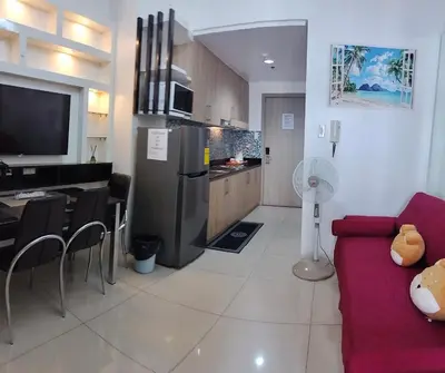 a living room with a red couch and a kitchen at Carps Staycation in Manila