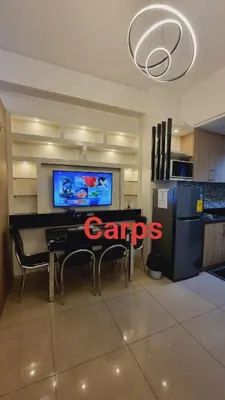 a kitchen with a table with chairs and a tv at Carps Staycation in Manila