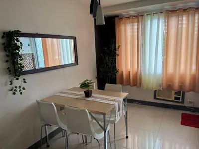 a dining room table with white chairs and a window at Sea Residences Spacious Unit by Ellenn in Manila