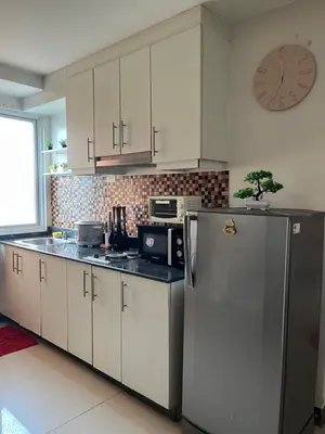 a kitchen with a refrigerator and a clock on the wall at Sea Residences Spacious Unit by Ellenn in Manila