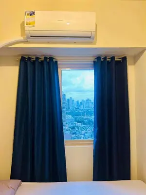 a bedroom with a window with a blue curtain at Zeke's Staycation in Manila