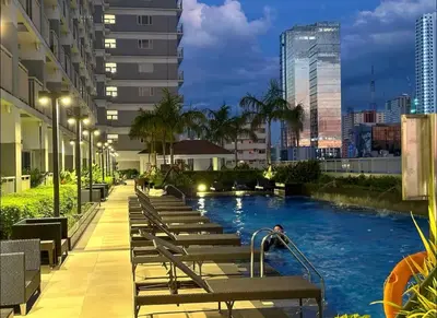 a hotel swimming pool in a city at night at Zeke's Staycation in Manila