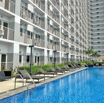 a swimming pool in front of a large building at Zeke's Staycation in Manila