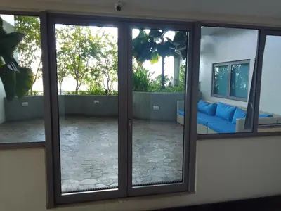 a room with sliding glass doors with a blue couch at Aveline Suites Sunrise 2bedroom in Manila