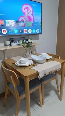 a wooden table with two chairs and a tv at Cozy Space at Red Makati City in Manila
