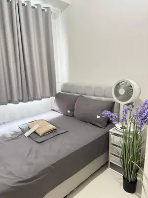 a bedroom with a bed with a fan and flowers at Unistay Shore 3 Tower 2 10th floor near MOA and AIRPORT in Manila