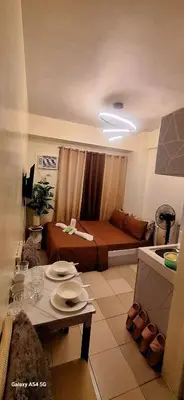 a small living room with a bed and a table at g and A condotels in Manila