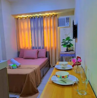 a small room with a bed and a table with dishes at g and A condotels in Manila