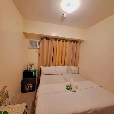 a small bedroom with a bed and a window at g and A condotels in Manila