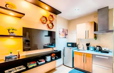 a kitchen with yellow walls and a refrigerator at Poblacion Stay with Pool Gym Jacuzzi and Pool Table in Manila