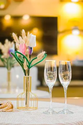 two wine glasses and a vase with flowers on a table at Poblacion Stay with Pool Gym Jacuzzi and Pool Table in Manila