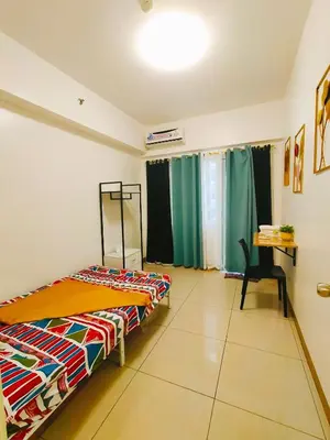 a room with two beds and a desk in it at Cozy 2BR Stay Near SM Southmall in Manila