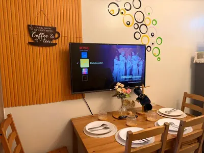 a television on a wall above a wooden table at Shore 2 Tower 1 Eliel Staycation in Manila