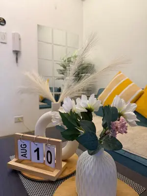 a vase with flowers on a table next to a clock at Shore 2 Tower 1 Eliel Staycation in Manila
