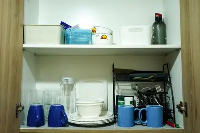 a cupboard with blue mugs and other items on it at Shore 2 Residences near MOA, NAIA, PITX in Manila