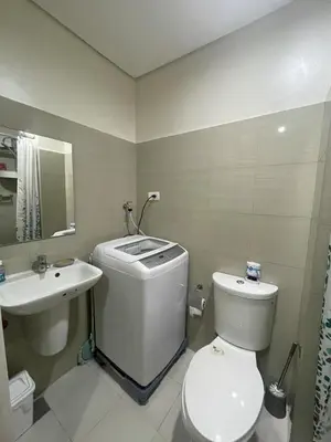 a white bathroom with a toilet and a sink at Shore 2 Residences near MOA, NAIA, PITX in Manila