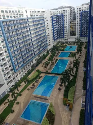 an overhead view of a row of swimming pools with buildings at Sea residence in Manila