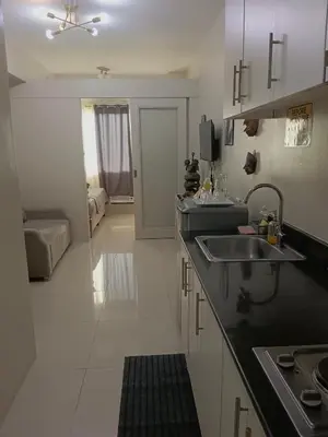 a kitchen with a sink and a living room at Sea residence in Manila