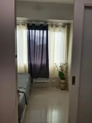 a bedroom with a bed and a window with curtains at Sea residence in Manila