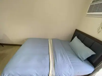 a bed with blue sheets and a pillow in a room at Bright Condo-Gentry Manor 2 mins to Okada - 6G in Manila
