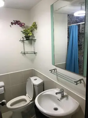 a bathroom with a toilet and a sink and a mirror at A venue Residences 2013 in Manila