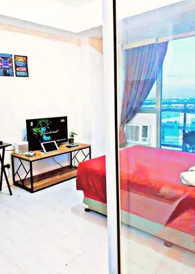 a living room with a bed and a desk with a computer at Azure Staycationcation by Nairah in Manila
