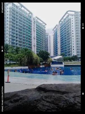 a group of people swimming in a pool with tall buildings at Azure Staycationcation by Nairah in Manila
