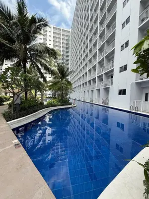 a large swimming pool in front of a tall building at 1 Bedroom Shore Residences 2 For Rent in Manila
